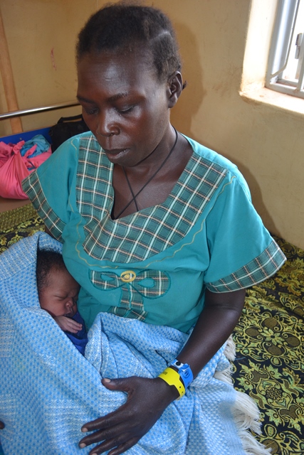 Night cuddles her new baby at Padibe Health Centre IV post-natal ward in Lamwo.