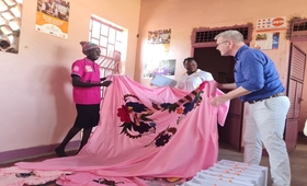 Danish Minister for Development Cooperation, Flemming Møller Mortensen checks out a bedcover that is made by women at Nyumanzi W