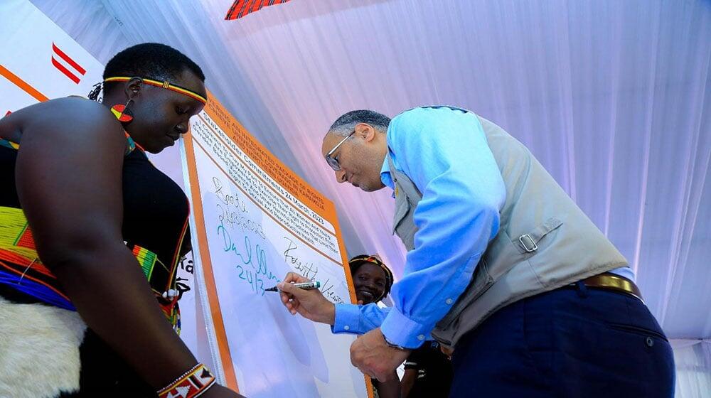 UNFPA Uganda Deputy Representative Me Daniel Alemu signs the commitment board during the launch of the ADA II project in Moroto